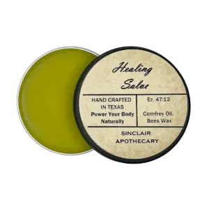 Open tin of handcrafted healing salve with comfrey oil and beeswax, eco-friendly packaging.